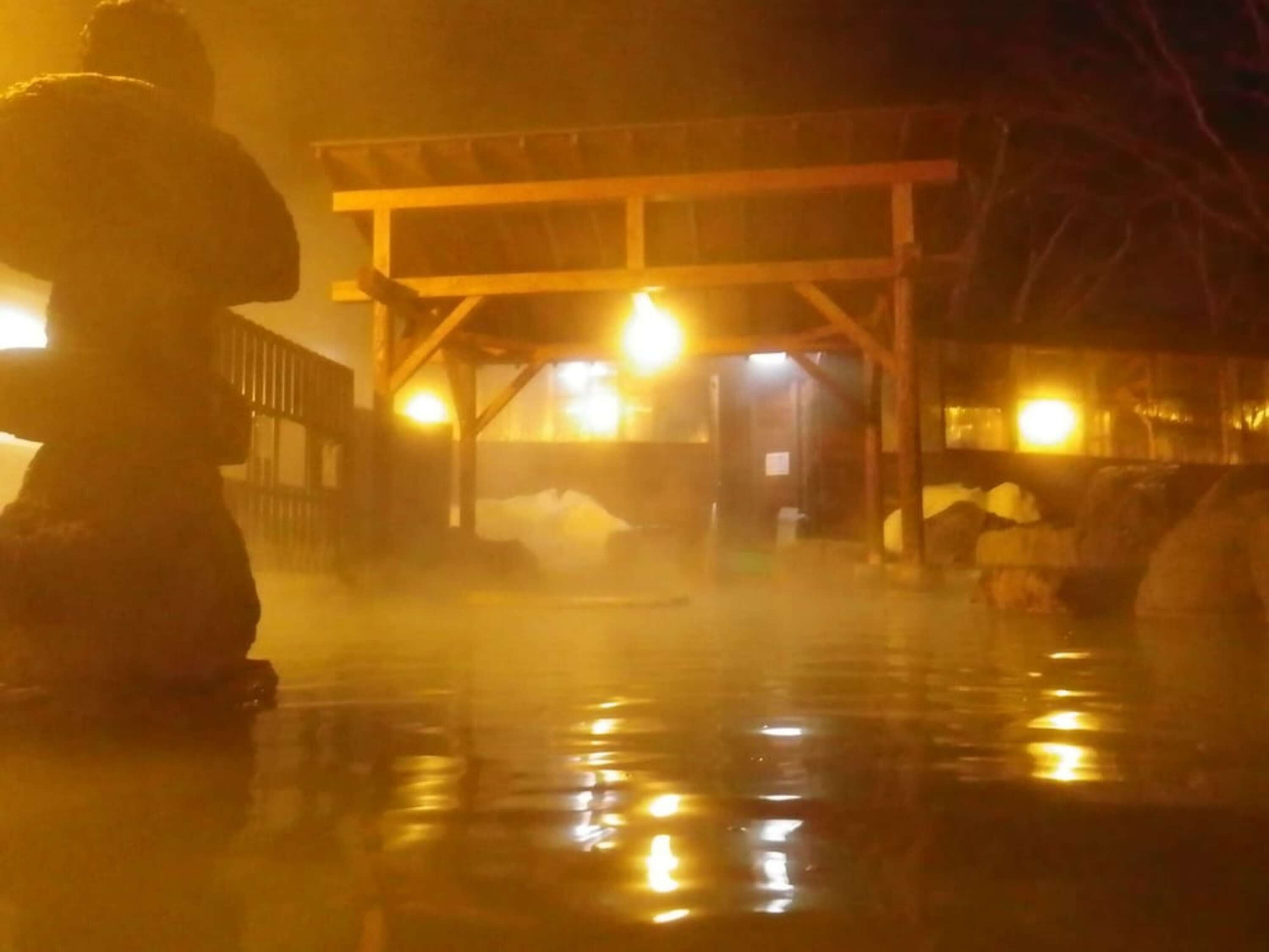 A traditional Japanese onsen with a wooden structure and a stone statue.