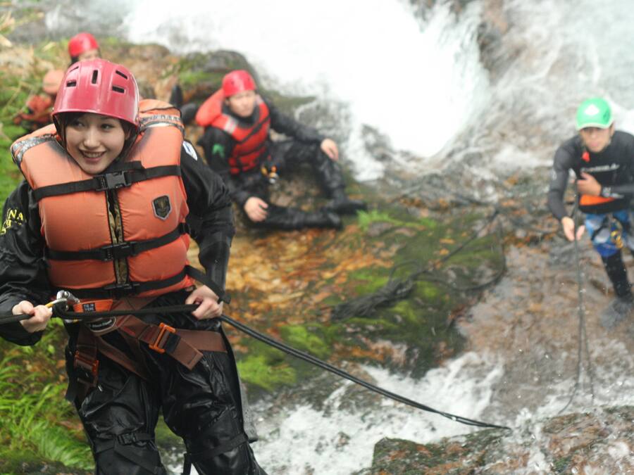 Un grupo de personas con equipo de exterior, incluyendo chalecos salvavidas y cascos, cerca de una cascada.