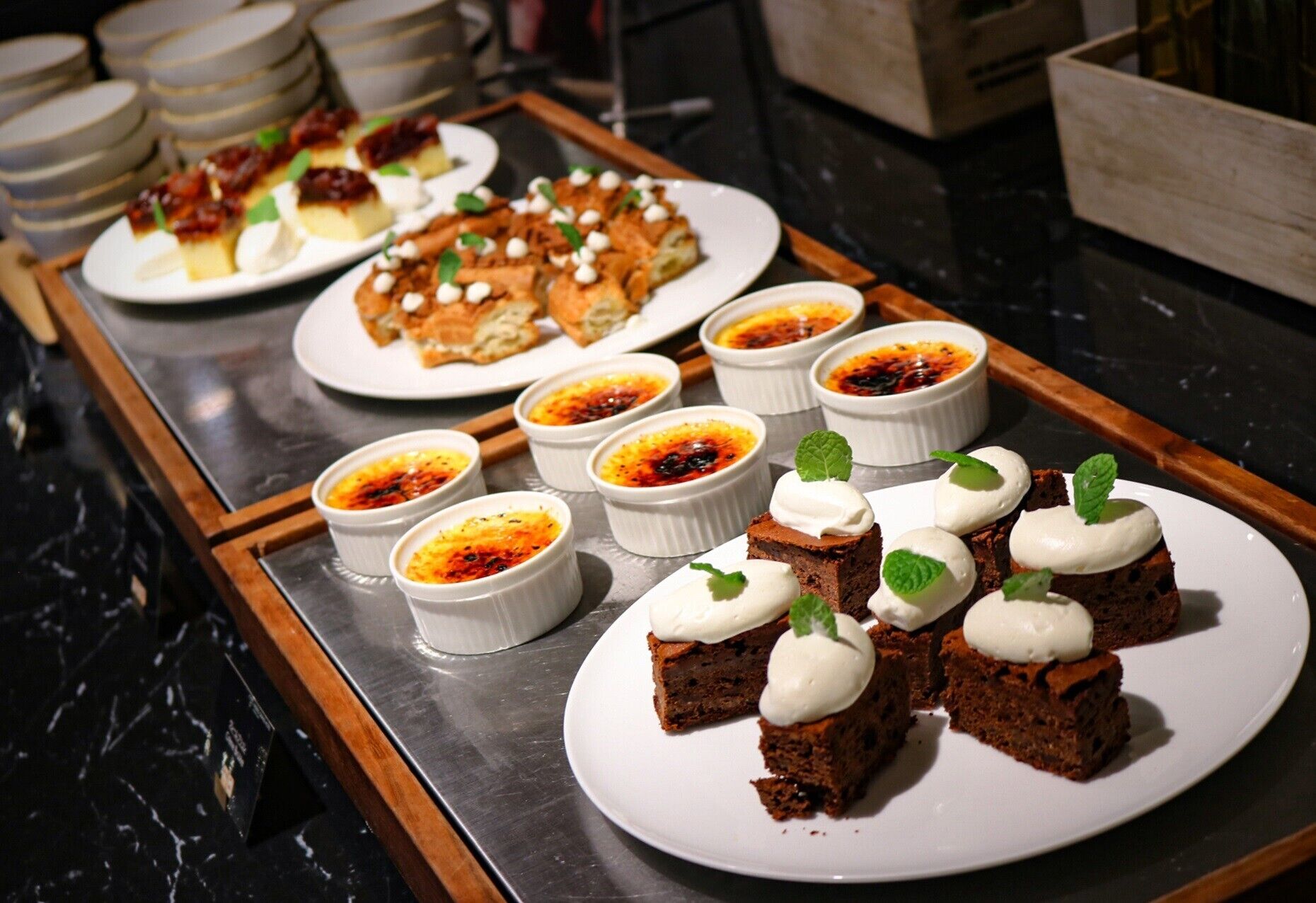 Un bufé con diversos postres, incluyendo crème brûlée, brownies y otras pastelerías.