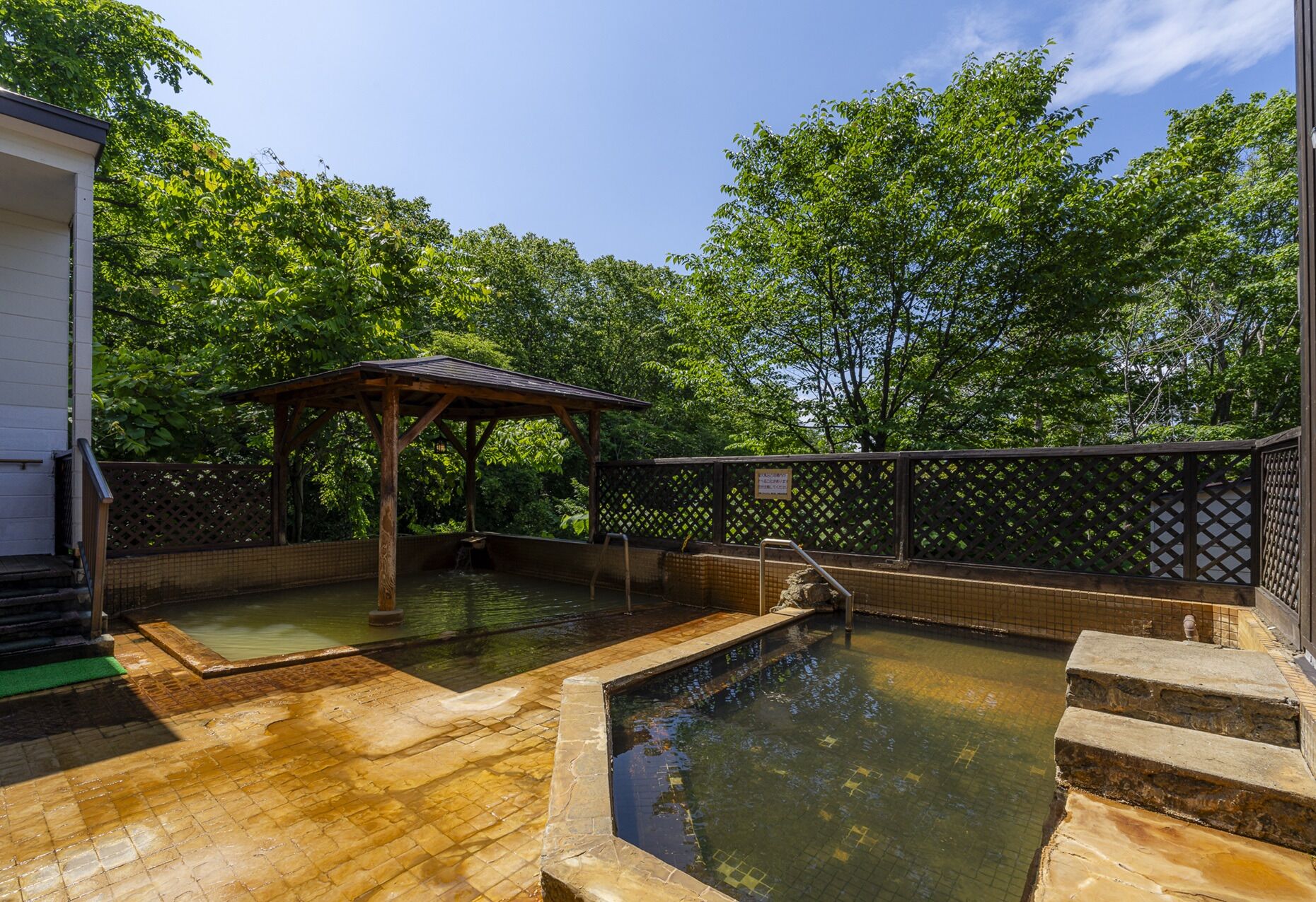 A traditional Japanese onsen with wooden walkways and a covered seating area.