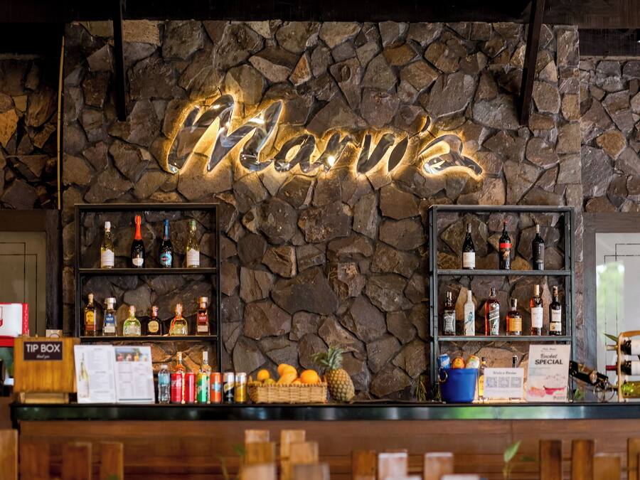 A bar area with a stone wall, shelves of liquor bottles, a 'Tip Box' sign, and a menu board.