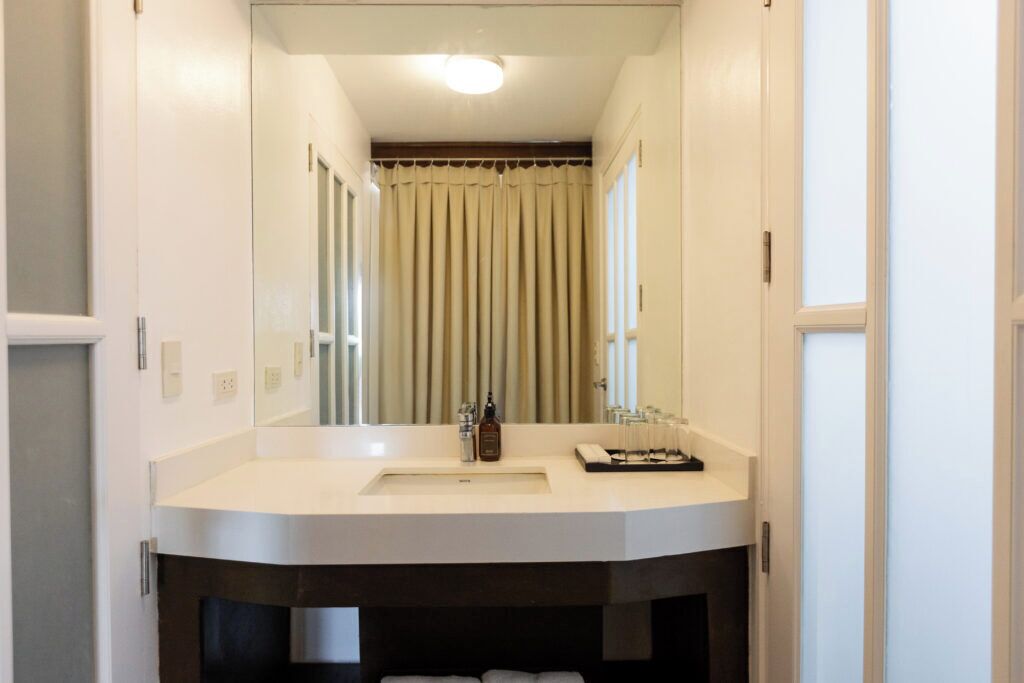 Une salle de bain avec un lavabo blanc, un miroir et un porte-serviettes.