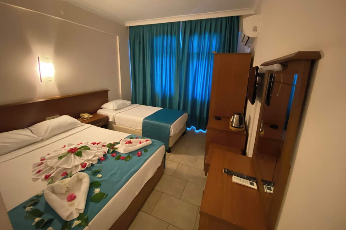 Une chambre d’hôtel avec deux lits, une armoire en bois, un bureau et une salle de bain avec douche.