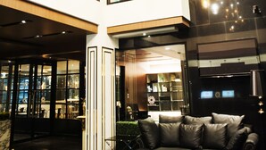 A modern hotel lobby with a high ceiling, large windows, and a central seating area with a sofa. - Marigold Sukhumvit (Samut Prakan)