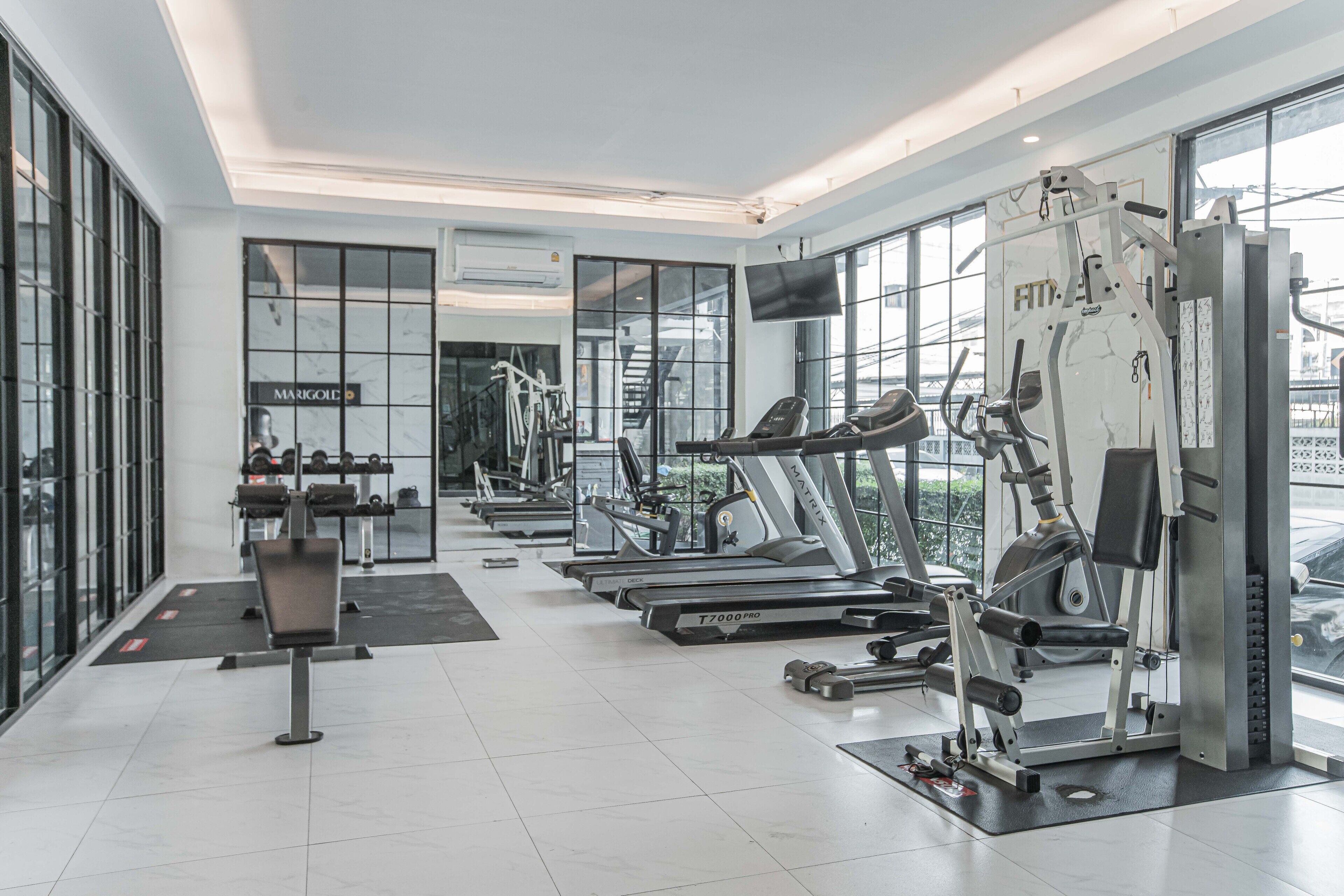 A modern gym with treadmills, weight machines, and a mirrored wall.