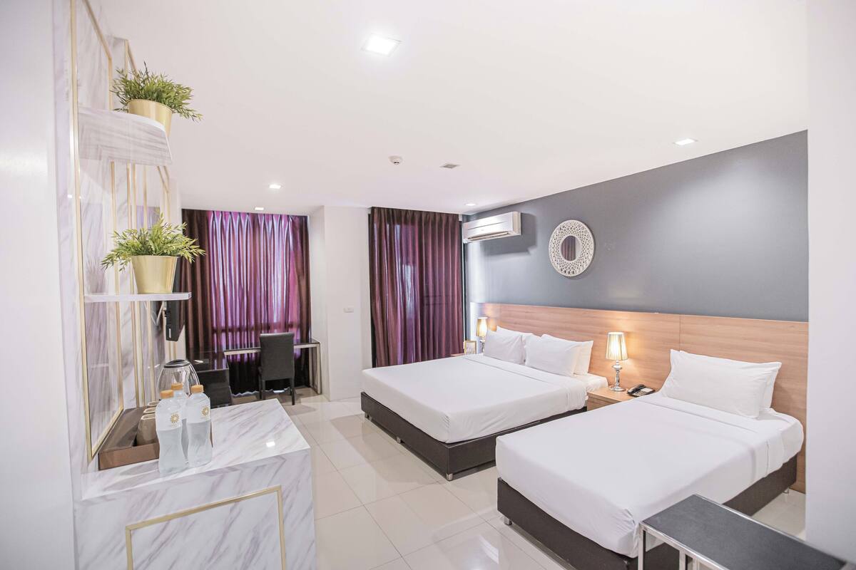 Una habitación de hotel moderna con dos camas, un tocador de mármol y un espejo grande.