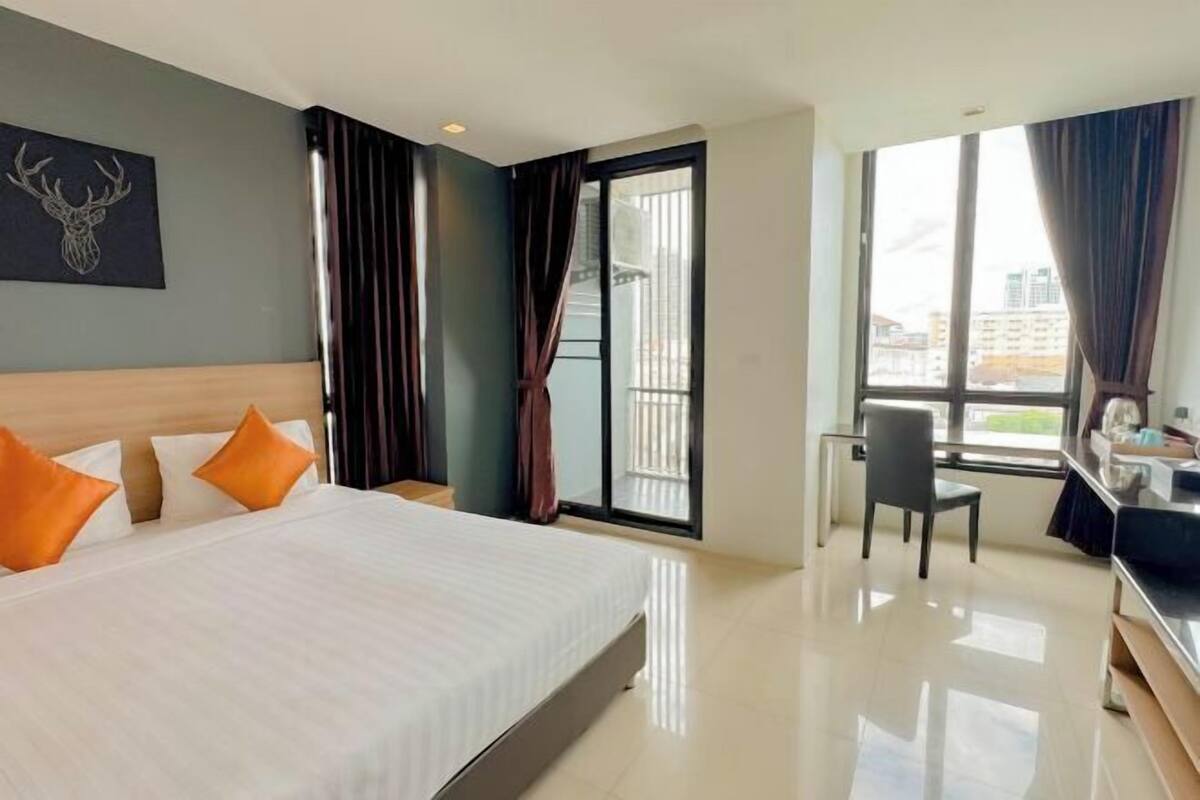 Habitación de hotel con cama, escritorio, silla, ventana grande y balcón.