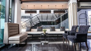 A modern lobby with a sofa, armchairs, a coffee table, and a staircase. - Marigold Sukhumvit (Samut Prakan)