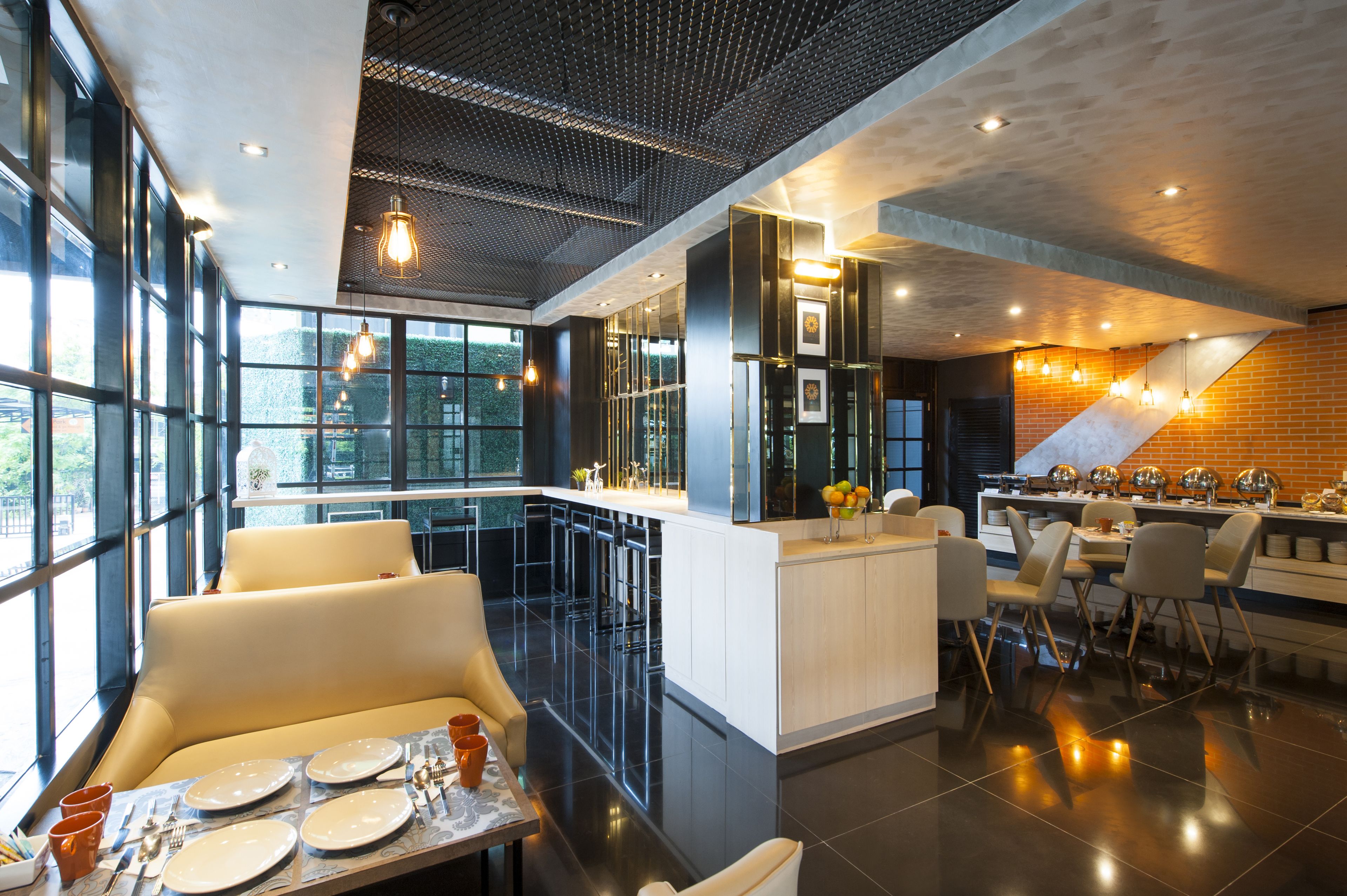 A modern restaurant with a bar area, seating, and a view through large windows.