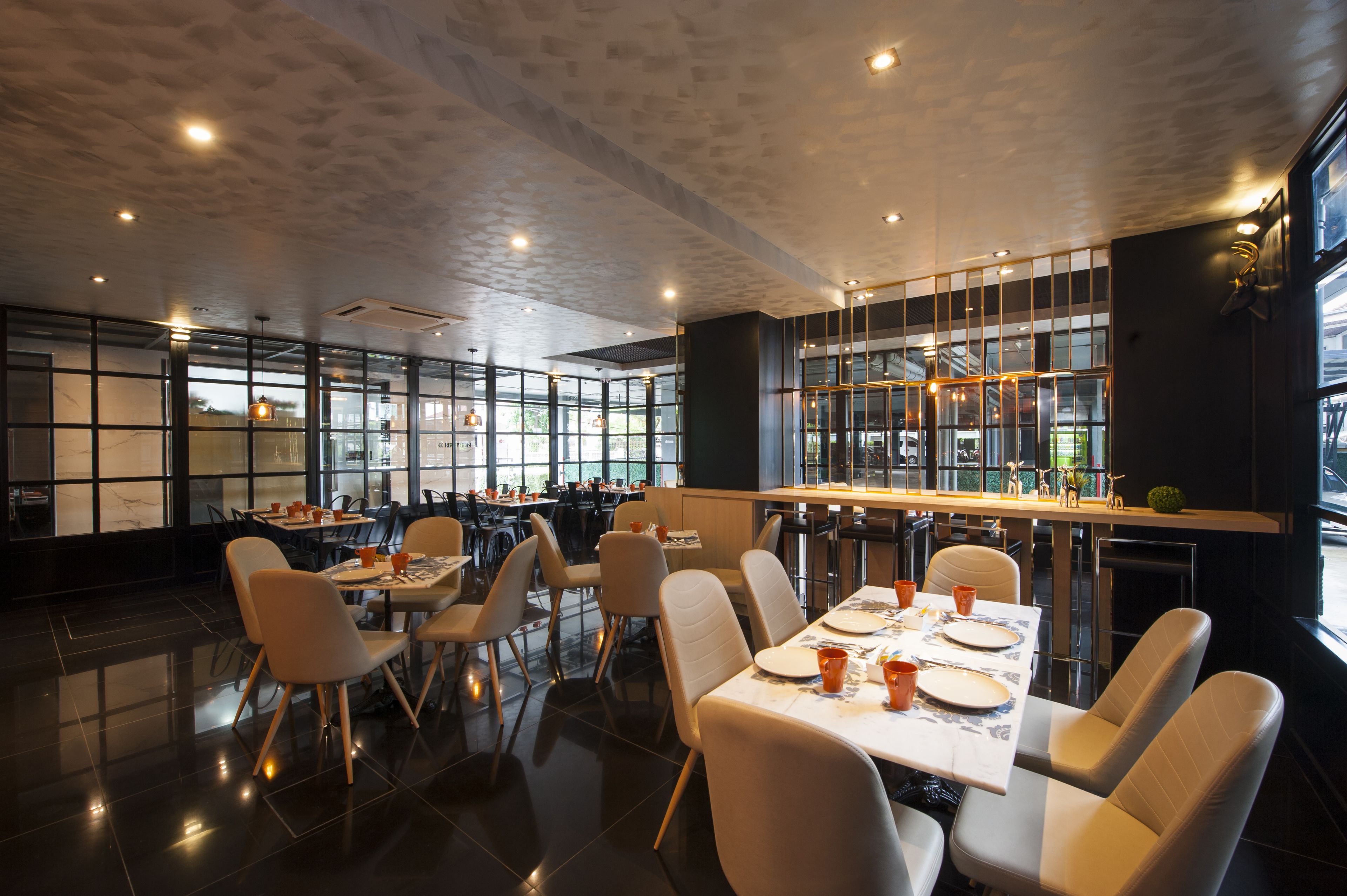 Un restaurante moderno con techos altos, ventanas amplias y una combinación de mesas y cabinas.