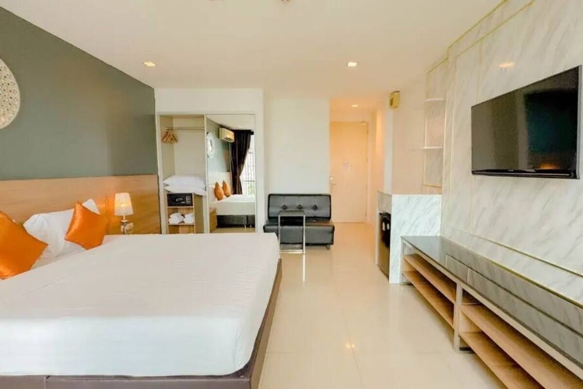 Una habitación de hotel moderna con una cama grande, un televisor de pantalla plana en la pared y un vestidor.