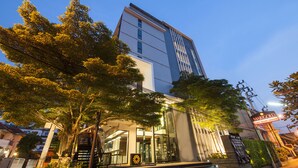 A modern hotel with a glass facade, a staircase leading to the entrance, and a sign indicating the name 'Marigold'. - Marigold Sukhumvit (Samut Prakan)