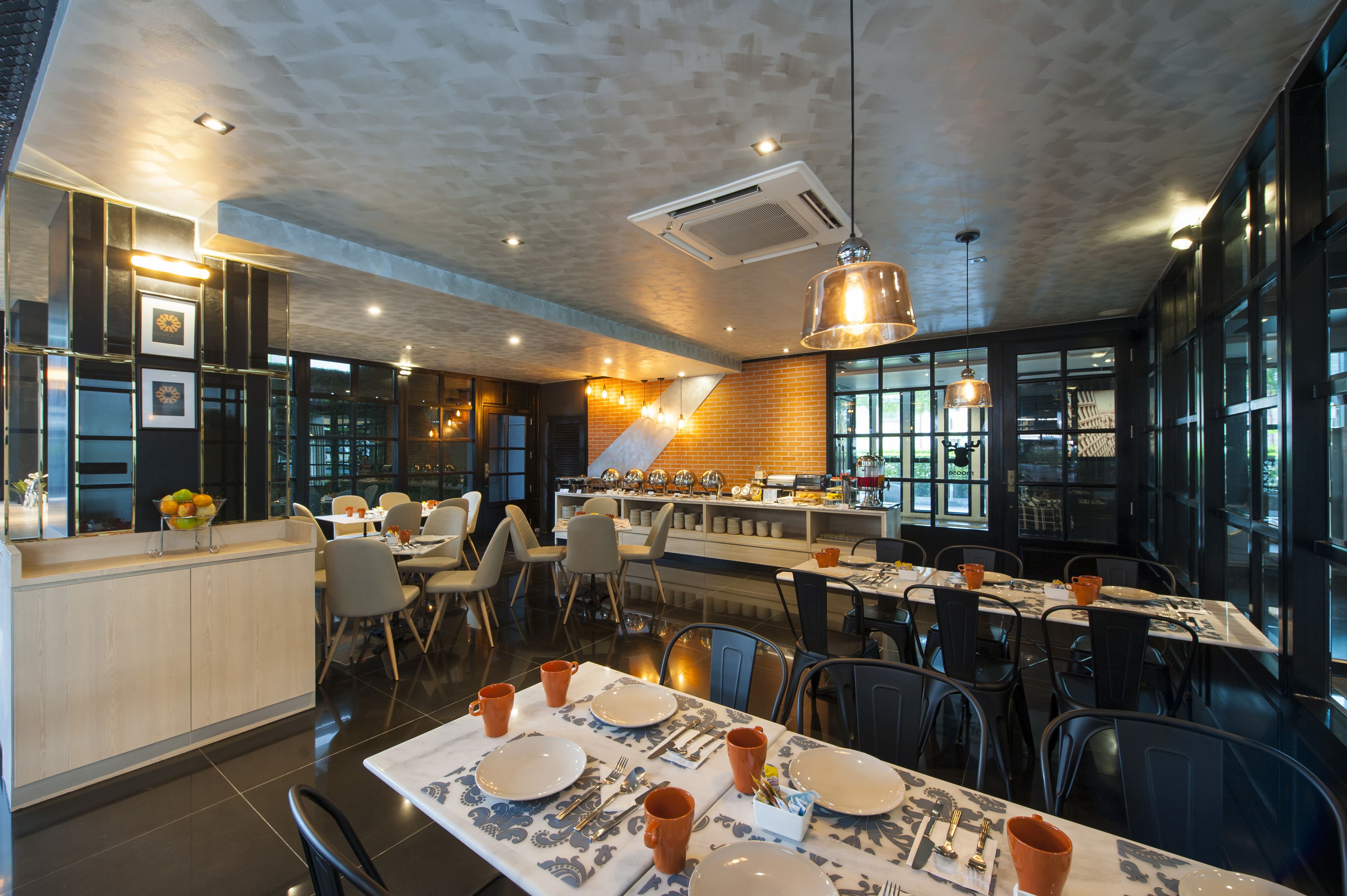 Un restaurante moderno con zona de bar, mesas de comedor dispuestas con platos y cubiertos, y una mezcla de sillas y taburetes.