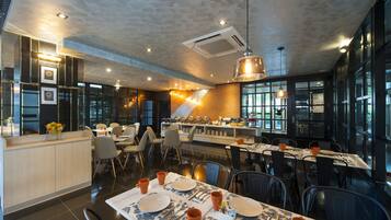 Un restaurante moderno con zona de bar, mesas de comedor dispuestas con platos y cubiertos, y una mezcla de sillas y taburetes.