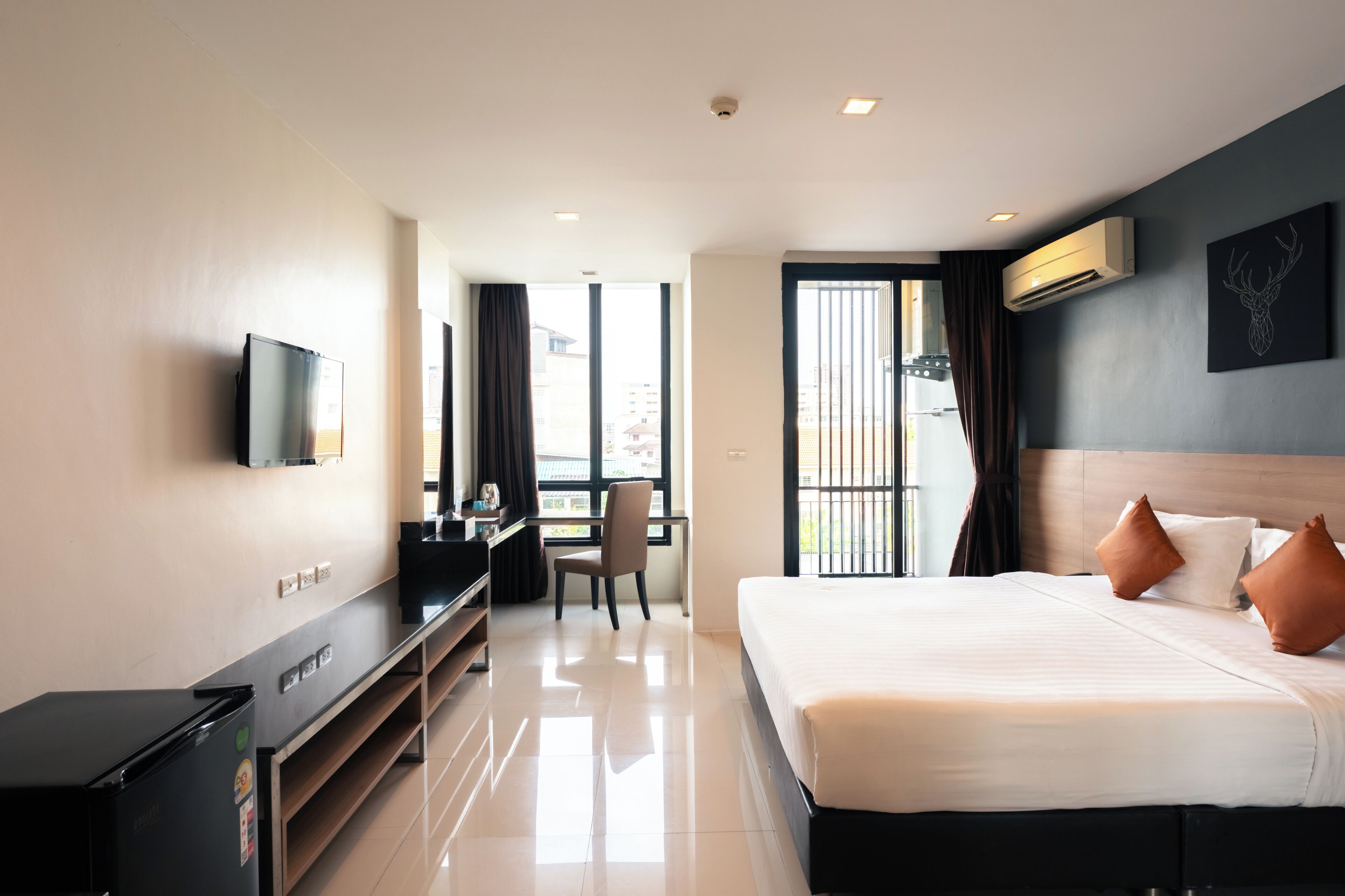 A hotel room with a bed, desk, chair, TV, and a balcony view.