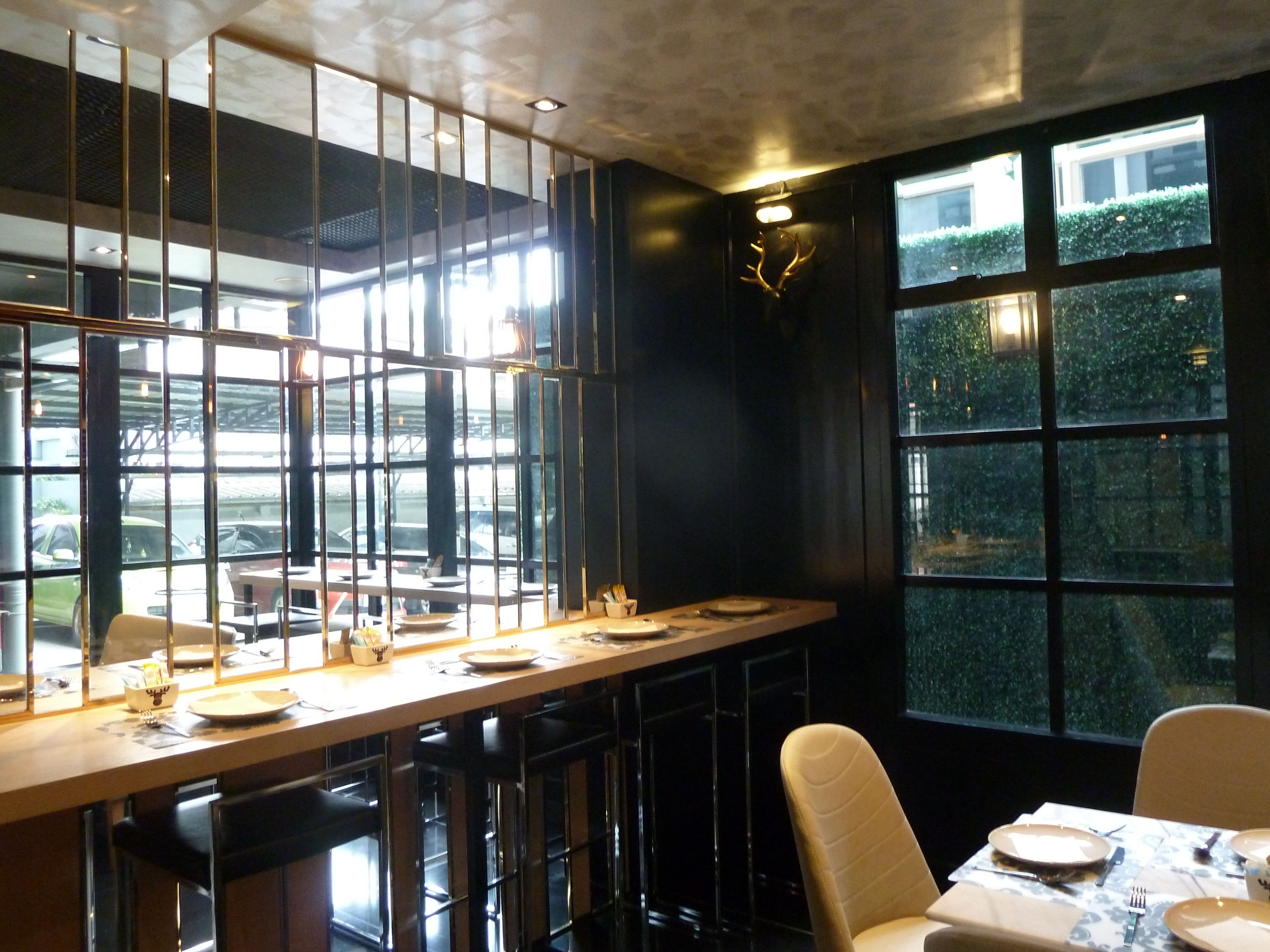 Ein Restaurant mit einer langen Theke, Barhocker und einem Tisch für zwei Personen.