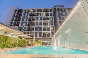 A modern building with a swimming pool, multiple balconies, and a waterfall feature. - Marigold Sukhumvit (Samut Prakan)
