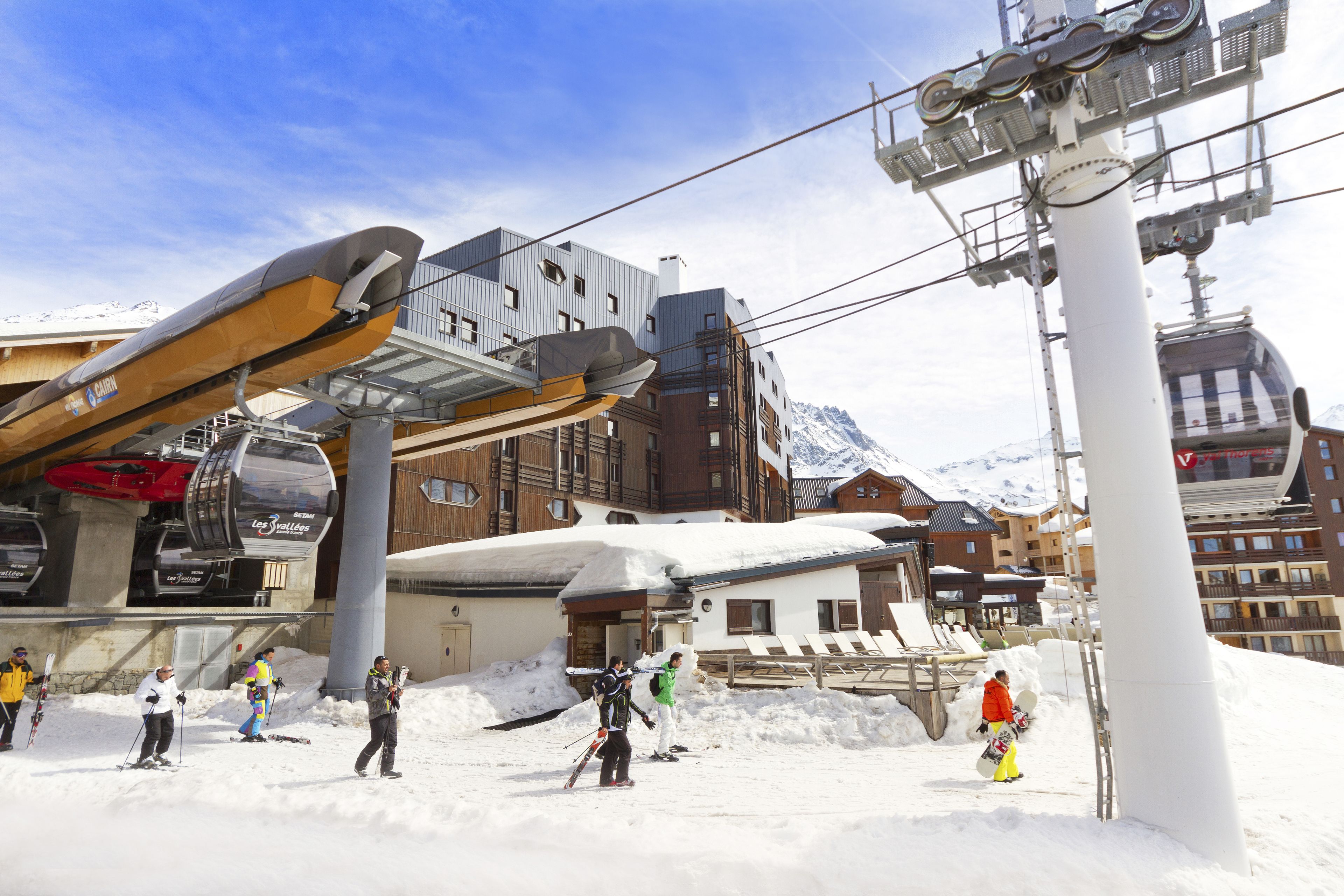 Estación de esquí con telesilla, montañas cubiertas de nieve y edificios con pistas.
