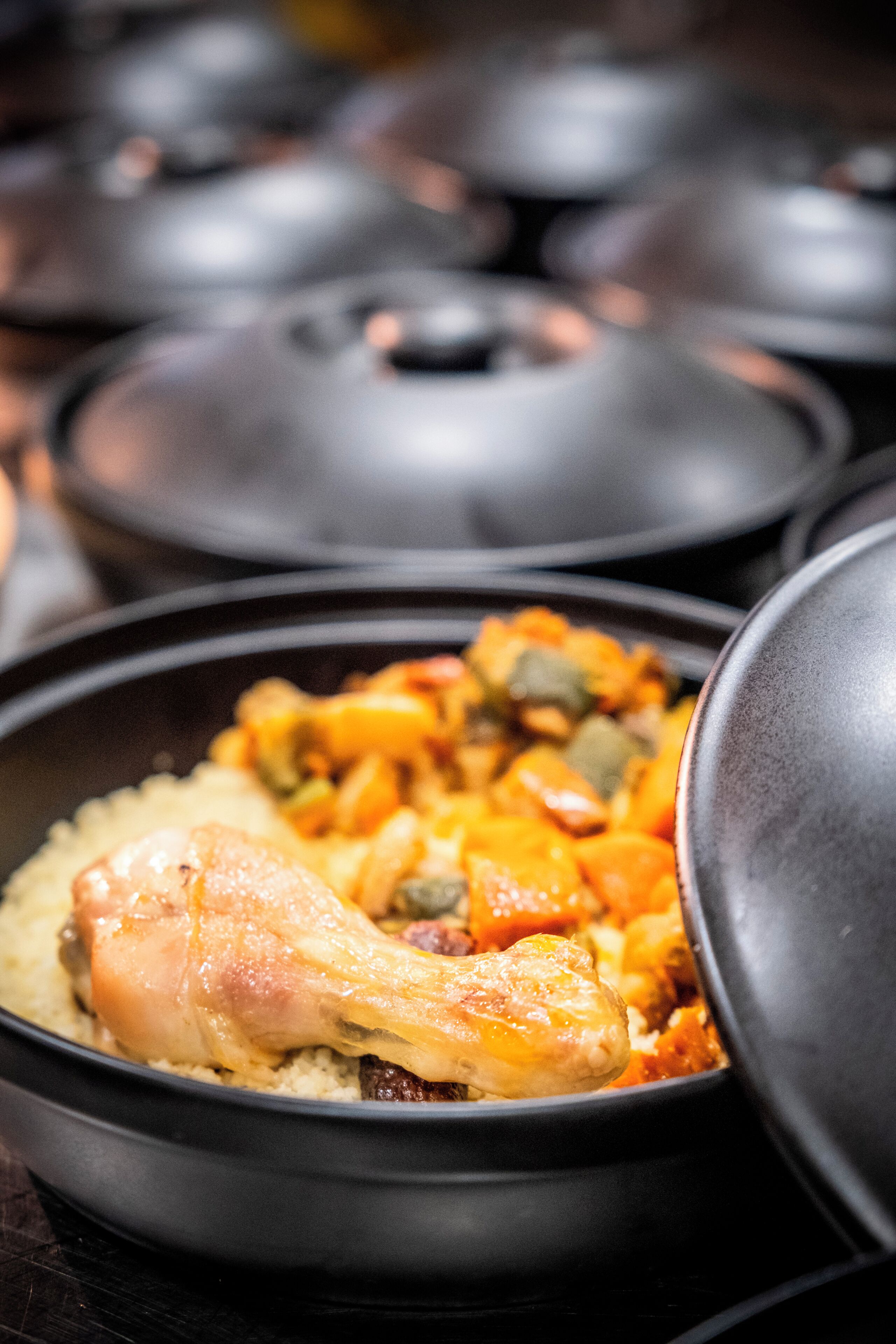 A close-up of a meal with a chicken leg and vegetables in a black bowl.