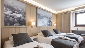 Habitación de hotel con dos camas, paneles de madera y grandes pinturas de paisajes en las paredes.