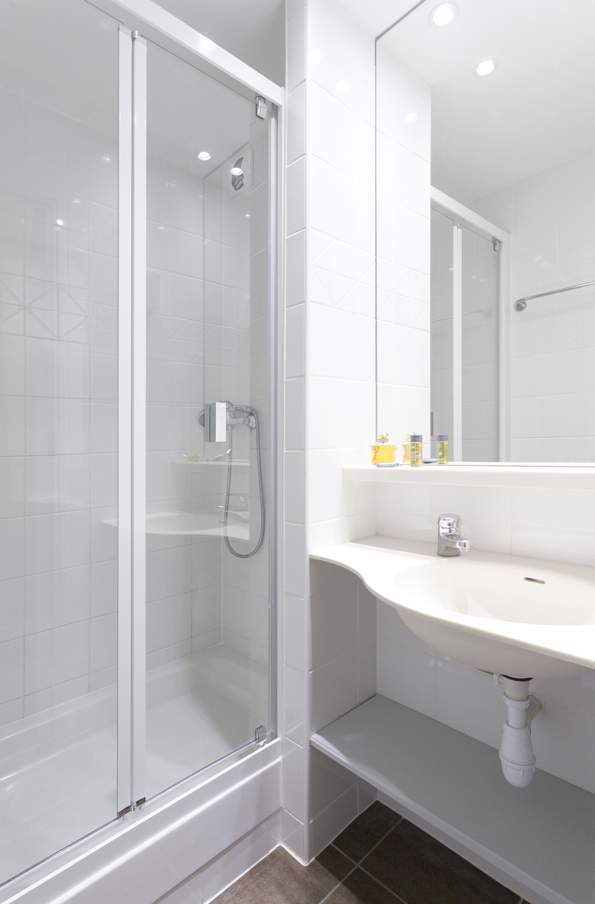 A modern bathroom with a glass-enclosed shower, a white sink, and a mirror above the sink.