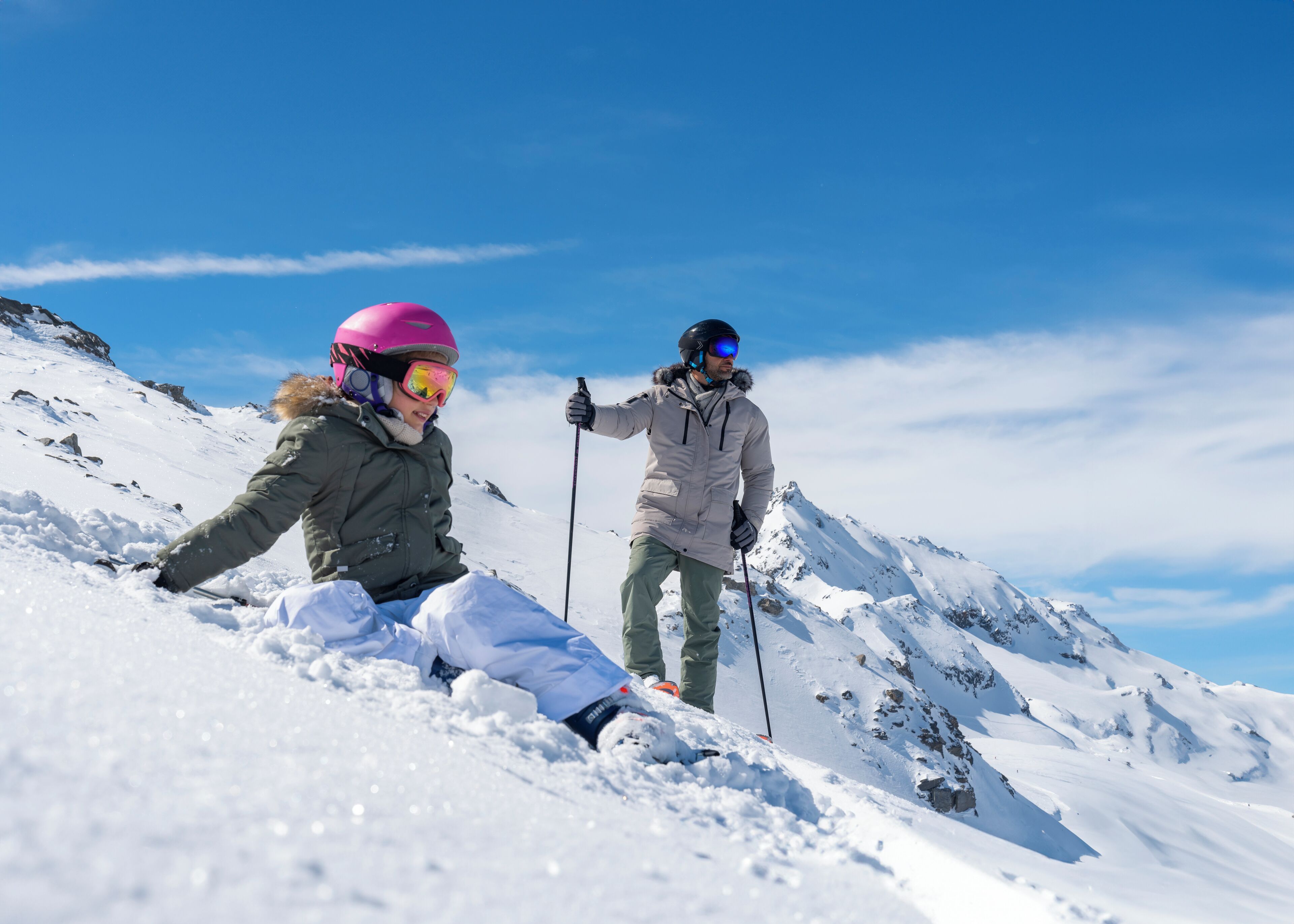 Two people skiing on a snowy mountain slope.