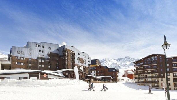 Un centro de esquí cubierto de nieve con edificios modernos, que incluye un telesilla y un restaurante.