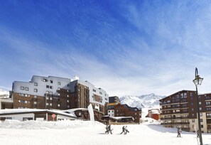 A snow-covered ski resort with modern buildings, including a ski lift and a restaurant. - Hôtel Club MMV Les Arolles (Les Belleville)