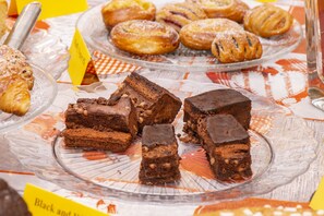 Une présentation de divers desserts sur un plateau en verre, notamment des brownies et des pâtisseries.