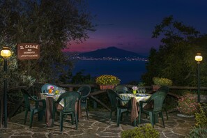 Un restaurant doté d’une terrasse offrant une vue panoramique sur une montagne et les lumières de la ville.