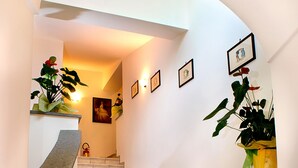 Een trap met beige tegels, een gebogen leuning en ingelijste foto's aan de muur.