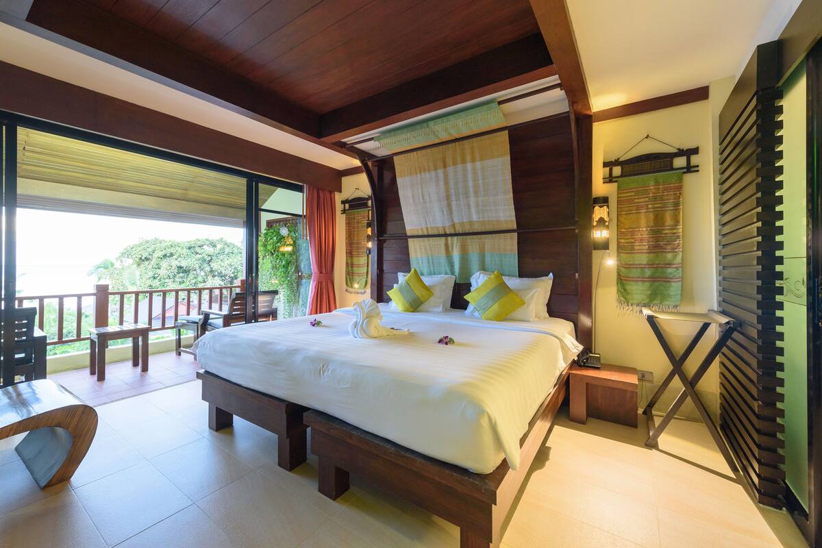 A spacious bedroom with a large bed, wooden headboard, and a view of the outdoors.