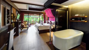 Een moderne hotelkamer met een groot bed, een badkuip, een eethoek en uitzicht op groen.