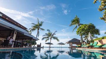 A poolside area with lounge chairs, umbrellas, and a bar area.