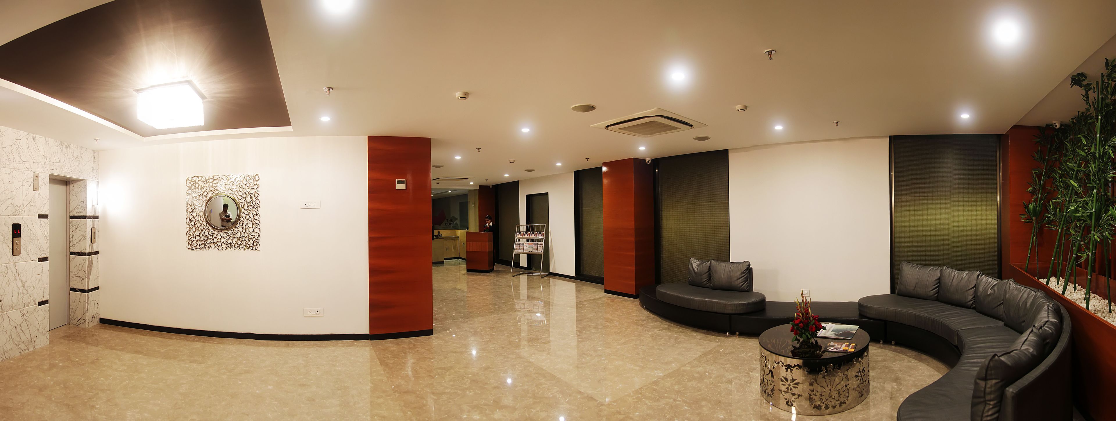 A modern lobby with a curved seating area, a reception desk, and a decorative wall piece.