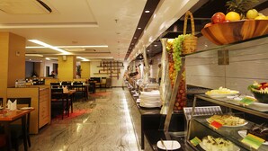 A buffet area with a variety of food items, a seating area with tables and chairs, and a decorative wall with hanging items. - Effotel by Sayaji Indore (Indore)
