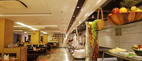 A buffet area with a variety of food items, a seating area with tables and chairs, and a decorative wall with hanging items.