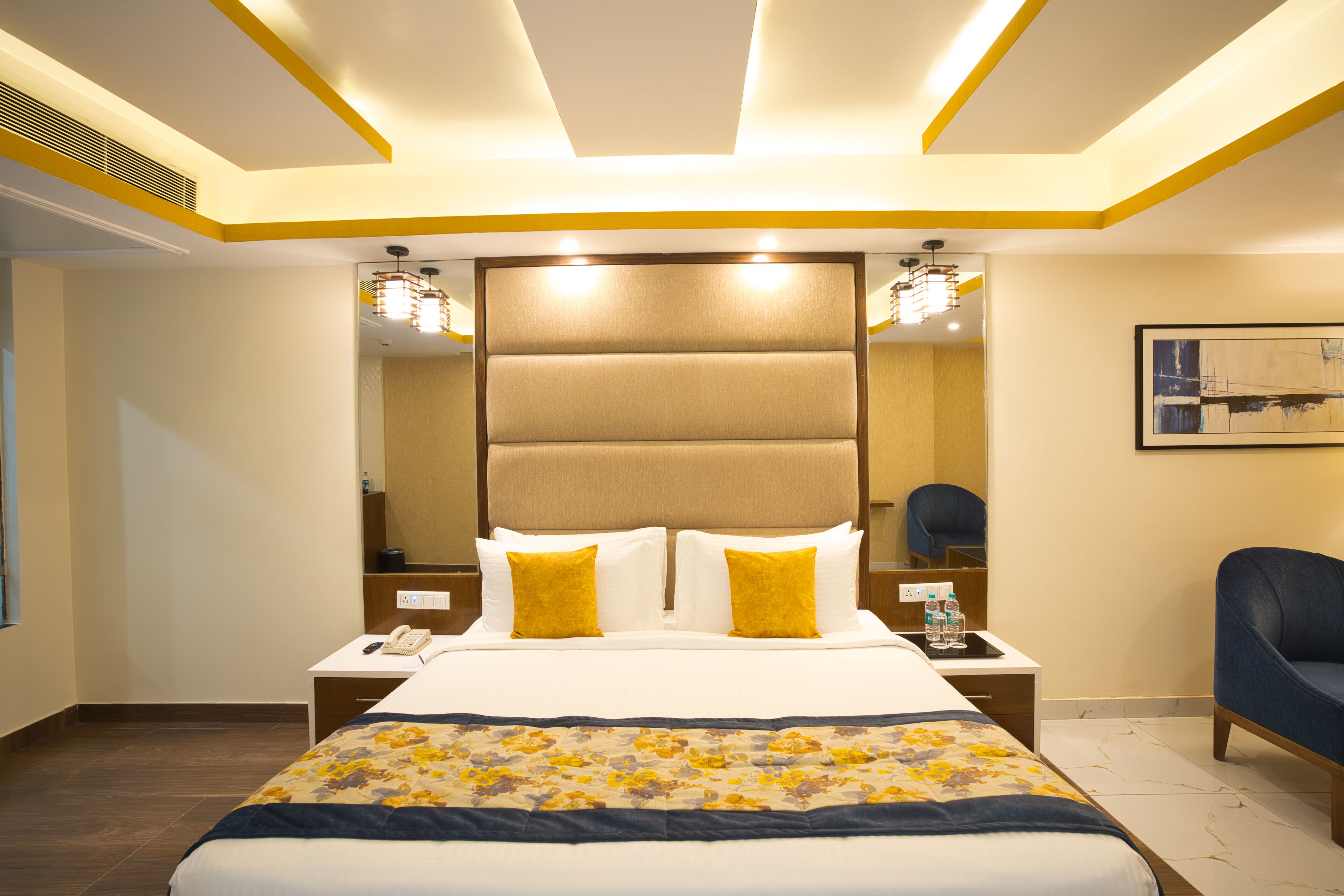 Una habitación de hotel con una cama grande, mesitas de noche, una silla y un cuadro en la pared.