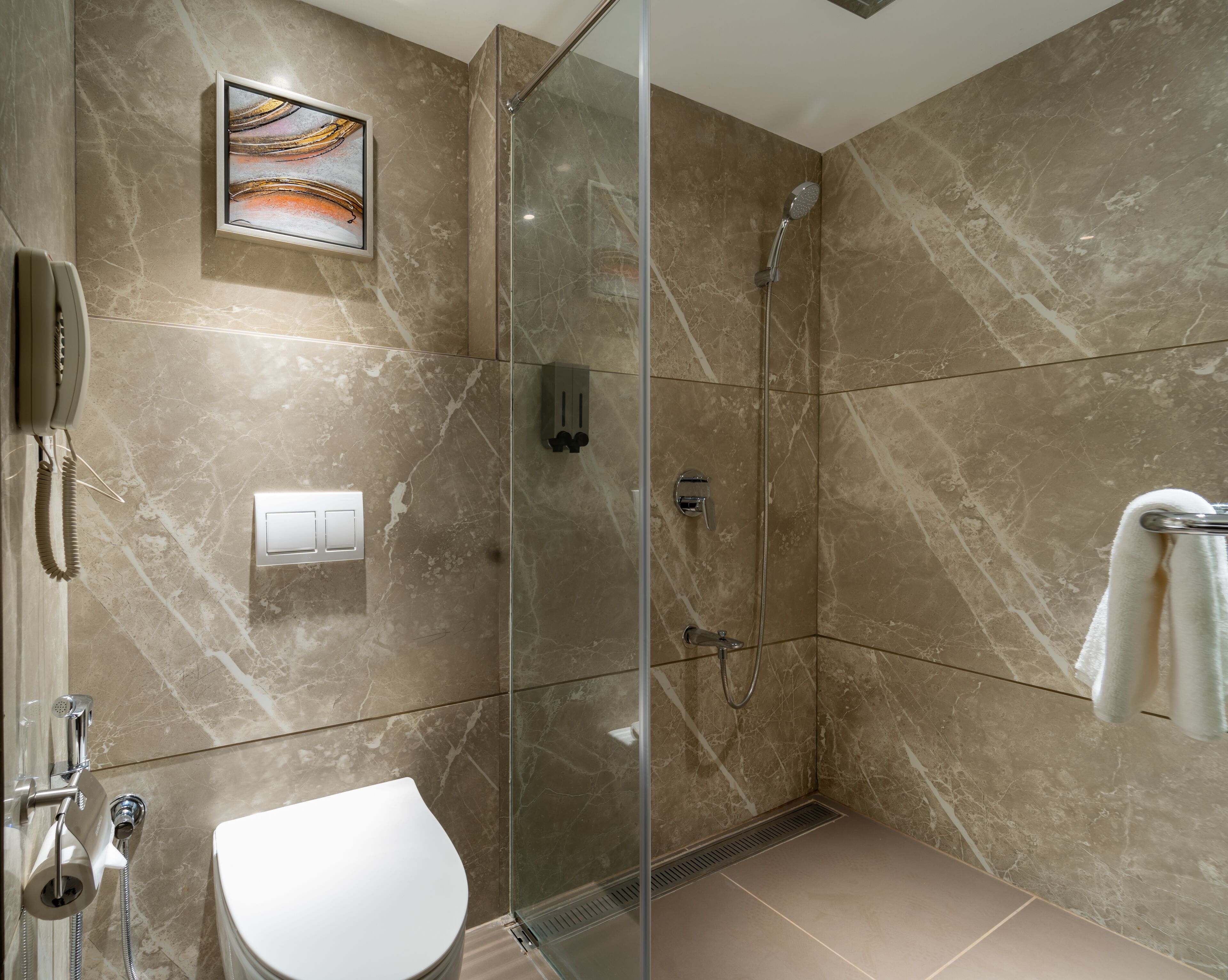 Une salle de bain moderne avec une douche à parois de verre, des toilettes et un porte-serviettes.
