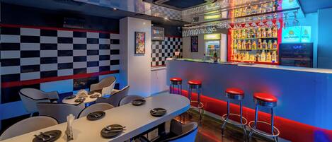 A bar area with a checkered wall, bar stools, and a well-stocked liquor shelf.