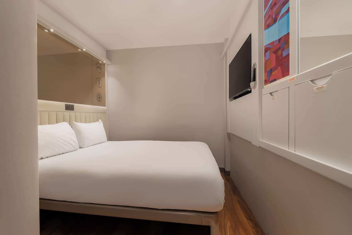 A small, neatly arranged bedroom with a bed, a television, and a cabinet.