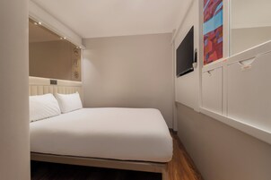 A small, neatly arranged bedroom with a bed, a television, and a cabinet.