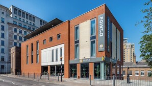 A modern hotel with a brick facade, large windows, and a visible entrance. - Point A London Canary Wharf  (London)