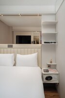 Ein Hotelzimmer mit einem Bett, Nachttischen, einem Spiegel und einem Regal mit Gegenständen.