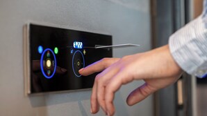 A hand interacting with a control panel on a door, featuring a digital display and several buttons. - Point A London Canary Wharf  (London)