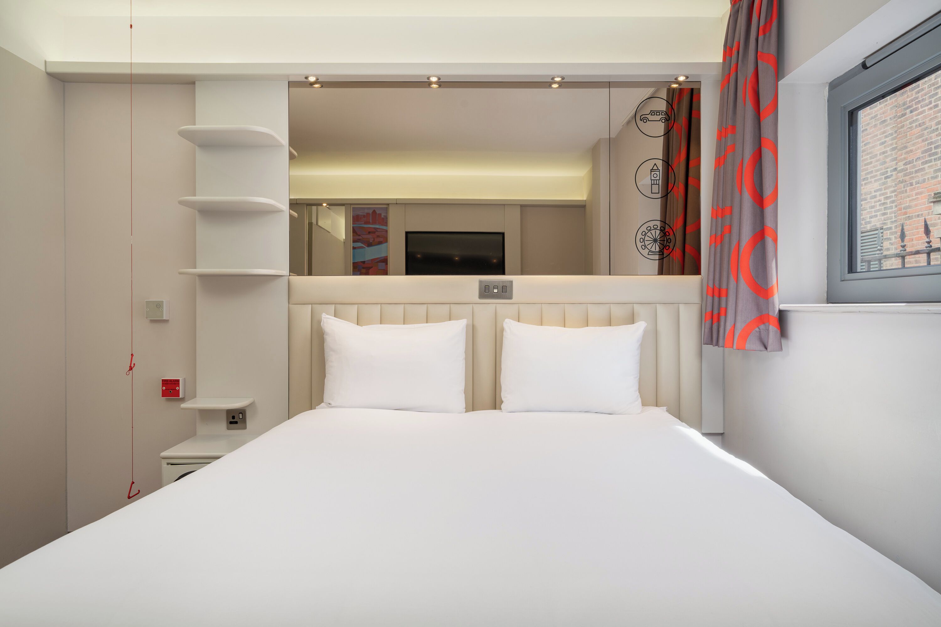 A modern hotel room with a large bed, a TV, a small bedside table, and a window with curtains.