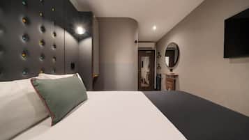 Een moderne hotelkamer met een groot bed, een ingebouwde hoofdbord met ronde verlichting, een flatscreen televisie en een spiegel aan de muur.