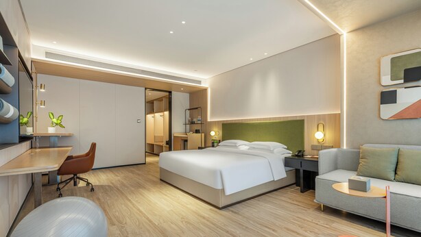 A modern hotel room with a bed, a desk, a chair, a sofa, and a small exercise ball. - EVEN Hotel Hangzhou Yintai City by IHG (Hangzhou)