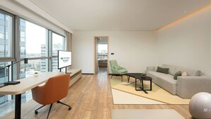 A modern hotel room with a large window, a desk, a comfortable sofa, a green chair, and a small exercise ball. - EVEN Hotel Hangzhou Yintai City by IHG (Hangzhou)