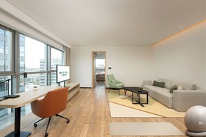 A modern hotel room with a large window, a desk, a comfortable sofa, a green chair, and a small exercise ball. - EVEN Hotel Hangzhou Yintai City by IHG (Hangzhou)
